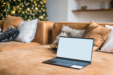 Wall Mural - Laptop on sofa with isolated white screen for mockup in Christmas time