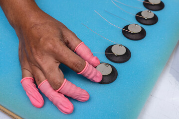 A factory worker double checking a set of piezoelectric diaphragms placed on a foam sheet. Example of quality control.