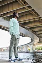 Wall Mural - Full length side view of young black man wearing headphones in urban city setting outdoors