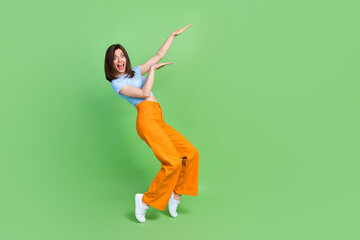 Wall Mural - Full length portrait of pretty satisfied person enjoy dancing hands make moves isolated on green color background
