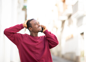 Wall Mural - Happy african guy talking on cellphone outdoors