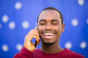 Wall Mural - Happy young black man talking on cellphone