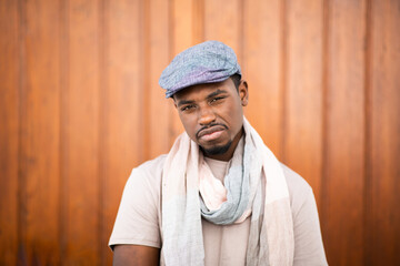 Wall Mural - Portrait of thoughtful young african man with cap and scarf