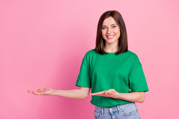 Wall Mural - Photo portrait of gorgeous young girl palms point empty space present new product wear stylish green look isolated on pink color background