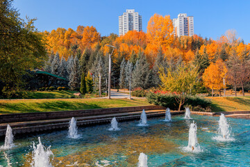 Beautiful view of trees with various colors and buildings on the background in Dikmen Valley | Dikmen Vadisi natural park in autumn in Ankara. Decorative water fountains in the big ornamental pool. 