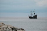 Fototapeta  - Little silhouette of sailing ship on horizon on sea