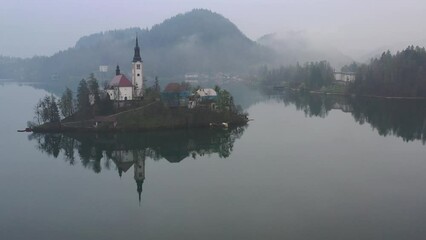 Poster - Aerial of the Assumption of Maria Church reflected in the Bled Lake in a foggy landscape