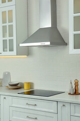 Elegant kitchen interior with modern range hood over cooktop and stylish furniture