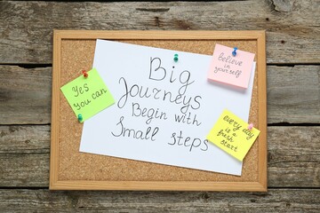 Wall Mural - Corkboard with motivational quotes on wooden table, top view