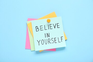 Wall Mural - Notes with phrase Believe In Yourself on light blue background, top view. Motivational quote