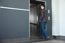 Young Businessman Entering Modern Elevator, Back View