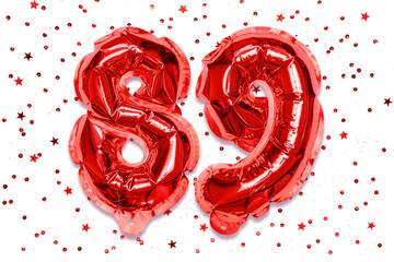 Wall Mural - The number of the balloon made of red foil, the number eighty-nine on a white background with sequins. Birthday greeting card with inscription 89. Numerical digit. Celebration event.