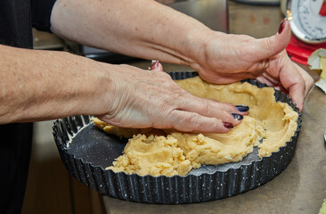 Wall Mural - Cook kneads the dough in a mold for making a pie in the kitchen