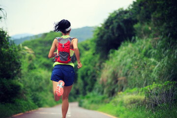 Wall Mural - young fitness woman trail runner running in forest mountain