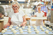 © Robert Kneschke - Ältere Bäckerin beim Brötchen backen am Belt Proofer