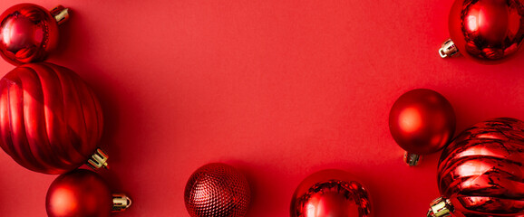 Wall Mural - Banner made of Red Christmas balls decoration on red background. New Year greeting card. Minimal style. Flat lay, top view, copy space.