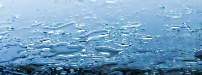 Pattern of water drops in a shiny metallic surface with table reflections