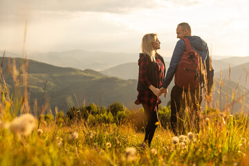 Canvas Print - Man and woman standing and hugging on the top of the mountain, autumn hike with backpacks