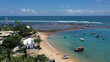 © MARCIA COBAR - Panoramic view of Praia do Forte beach near Salvador city with fishing boats, palm trees and a historic church. Praia do Forte, Bahia State, Brazil