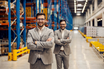 Wall Mural - Two successful managers are standing in warehouse with arms crossed.