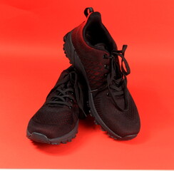 Black and red sport shoes theme in red color background. Pair of tennis shoes