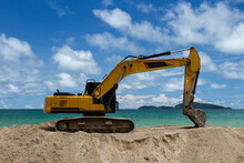 Excavator Is Scooping Up Sand On The Beach With Sky, Sea And Island Background..Excavator Is Digging Sand On The Beach.