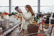 © vladdeep - Woman chooses a pot for home plants in a greenhouse store, hardware store