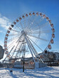 Ferris wheel Cracow Eye in the backlight against a blue sky with clouds on frosty winter day. Vertical bottom view. Krakow, Poland, Europe.