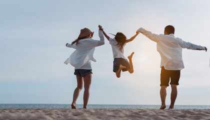 Wall Mural - Happy asian family jumping together on the beach in holiday vacation. Silhouette of the family holding hands enjoying the sunset on the sea beach. Happy family travel, trip  family holidays weekend.