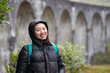 © ADDICTIVE STOCK - Smiling Asian female in warm jacket standing on street
