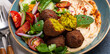 Close up of Middle Eastern Arab meal with fried falafel, hummus, vegetables salad with fresh green cilantro and mint leaves on ceramic plate on stone rustic background table. Arabic traditional cuisin