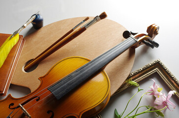 Painting, music, literature. Artist palette, brushes, violin, pipe, notepad, fountain pen, inkwell on a light background.