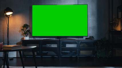 Fototapete - Stylish Loft Apartment Interior with TV Set with Green Screen Mock Up Display Standing on Television Stand. Empty Cozy Living Room of Spacious Flat with Chromakey Placeholder on Monitor.