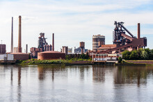 Integrated Steelworks On The Bank Of A River On A Partly Cloudy Summer Day