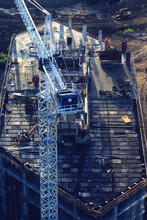 Aerial View Of Top Of High Rise Building Under Construction With Crane, Materials And Workers.