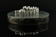 Close-up studio shot on milled metal frame for dental implants on the black background. Concept of new technologies in dental prosthetics