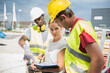 © Cavan Images - Architect reviewing blueprint with construction workers at building site