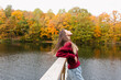 © Cavan Images - Girl in red sweatshirt standing by the lake in autumn park