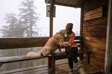 Cute Fluffy Dog And Girl Hug On Porch Of Cabin