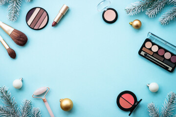 Poster - Make up products and christmas decorations on blue background. Holiday shopping sale concept. Flat lay image with copy space.