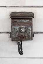 Old Fashioned And Worn Out Electrical Box Mounted Against A White Wall.
