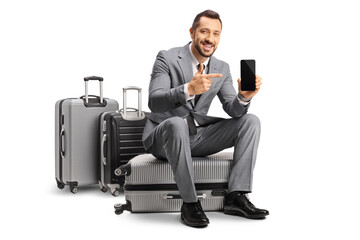 Wall Mural - Bussinessman sitting on a suitcase pointing at a smartphone