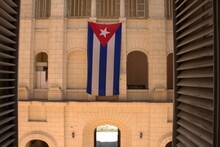 Flag Of Cuba Hanging Horizontally On A White Building
