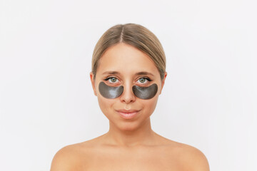 Sticker - Portrait of young attractive caucasian blonde woman with black gel glittering patches on the skin under her eyes isolated on a white background. Skin care, cosmetology. Beauty concept