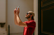 © Jimena Roquero/Stocksy - Man taking a picture with smartphone inside a building