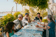 © Jimena Roquero/Stocksy - Multigenerational group of people sitting by restaurant terrace table