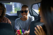 Woman With Shaved Head Smiling As She Uses Smartphone In Car