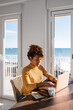 © Milles Studio/Stocksy - Hispanic female browsing laptop in sunlit apartment