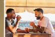 © Pedro Merino/Stocksy - Interracial gay couple having a drink on a terrace