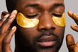© ohlamour studio/Stocksy - Man using gold eye patches close up